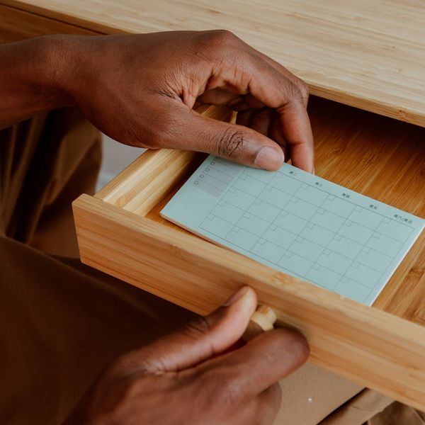 A neat and organized daily planner on a wooden desk next to a plant.